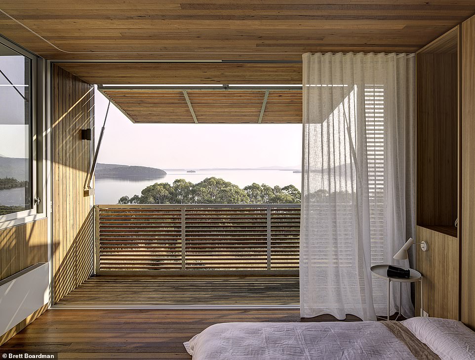 The master bedroom overlooks the water, capturing the view like a photograph in its enormous timber-framed windows